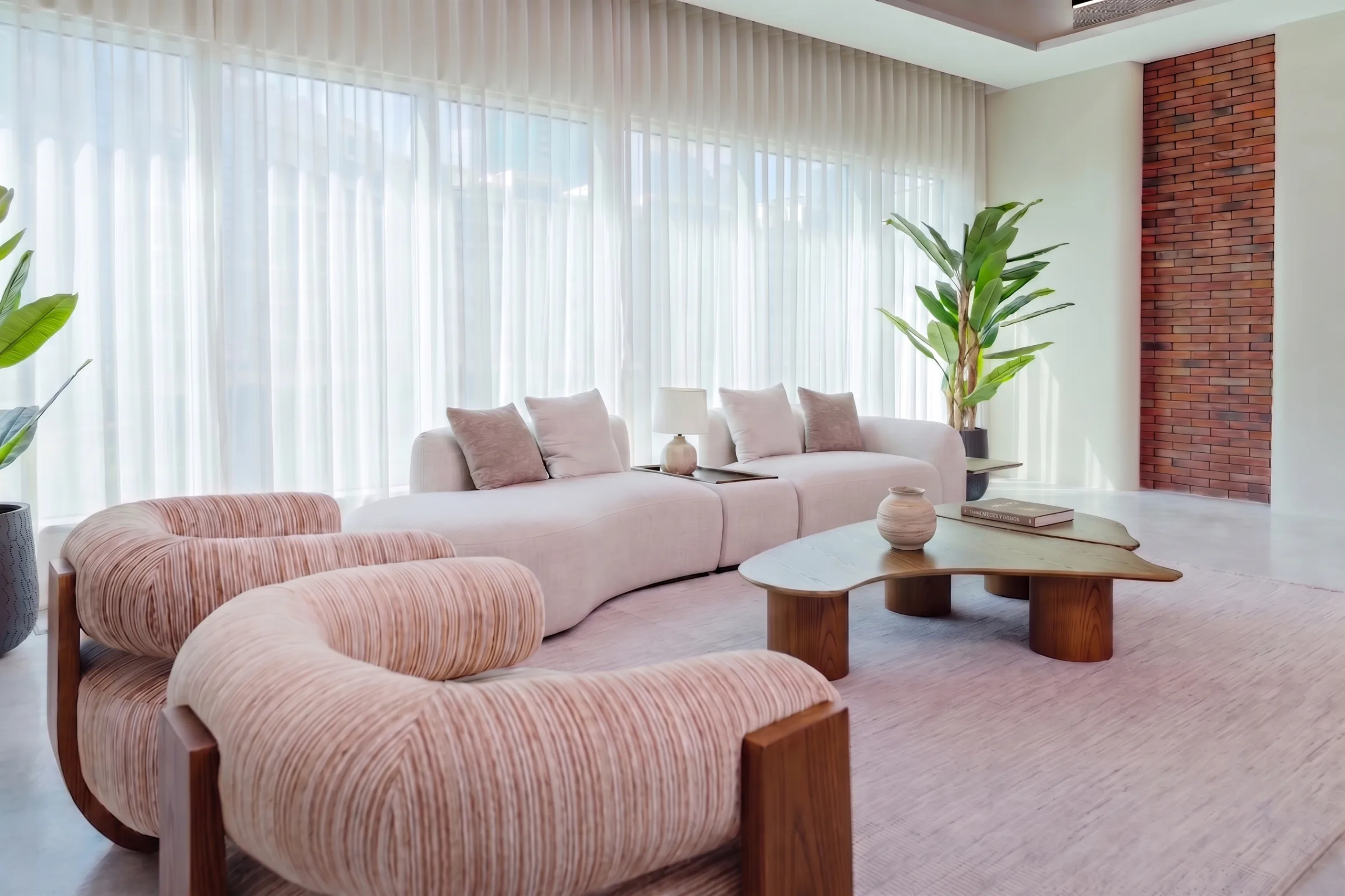 Aether at Legato Studio: curved cream sofa, striped armchairs and walnut tables in daylight from tall curtained windows