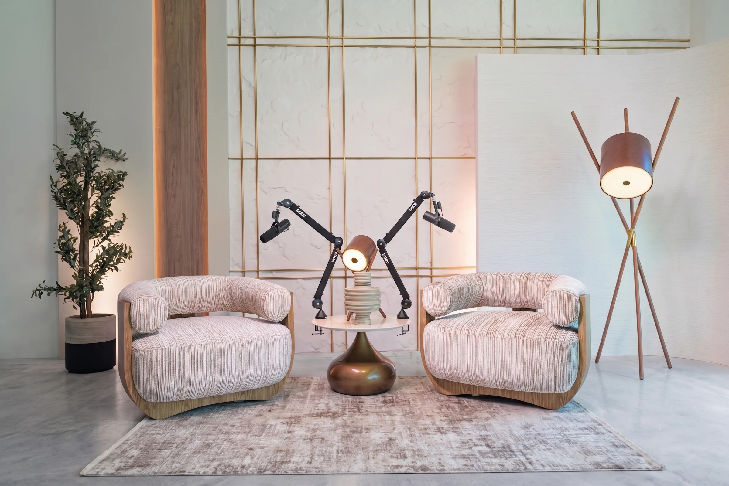 Carved studio at Legato Studio: two striped armchairs and podcast mic arms before a textured plaster wall with a brass grid