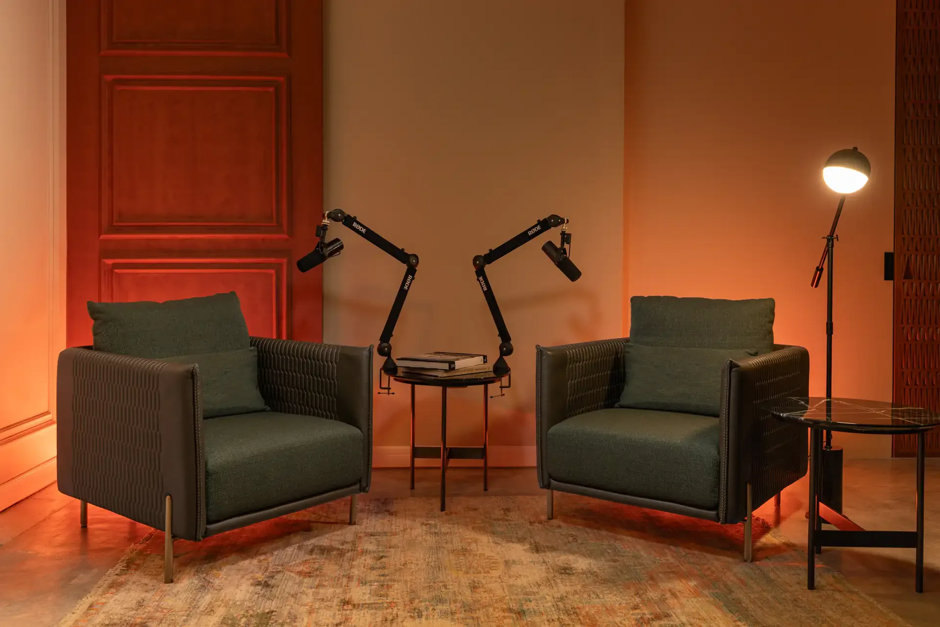 Portal studio at Legato Studio: green armchairs and podcast mic arms beside a tall panelled door in warm orange light