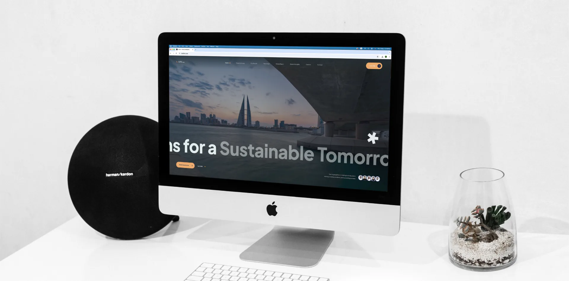 iMac on a white desk displaying the Alaali LexMaxima website homepage