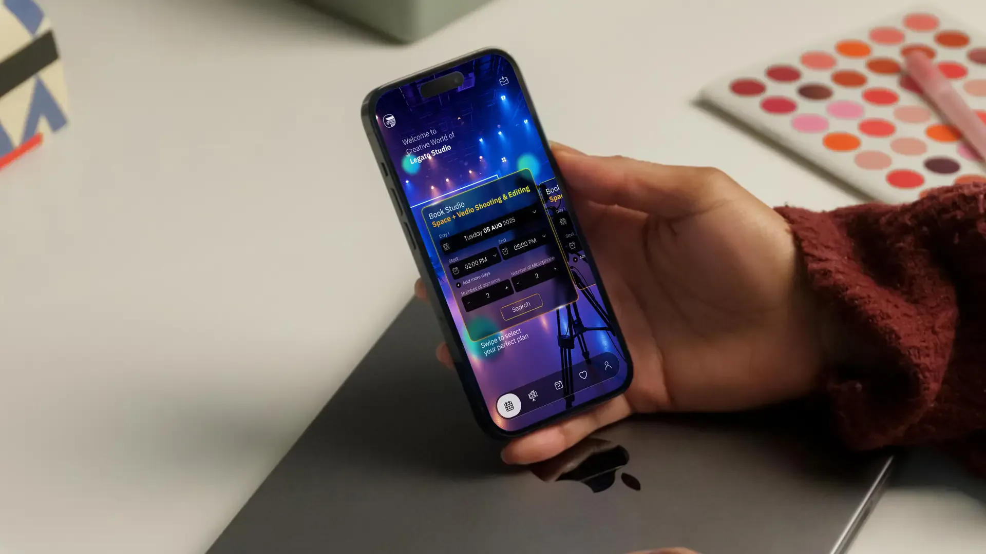 Person holding a phone with the Legato Studio app over a laptop, colour swatches on the desk