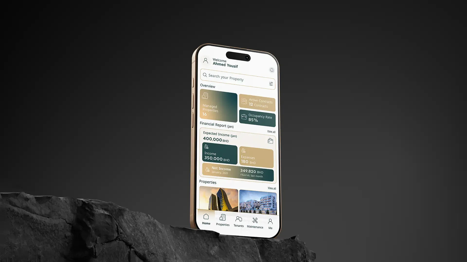 Gold iPhone balanced on a dark rock displaying the Mullak+ property dashboard